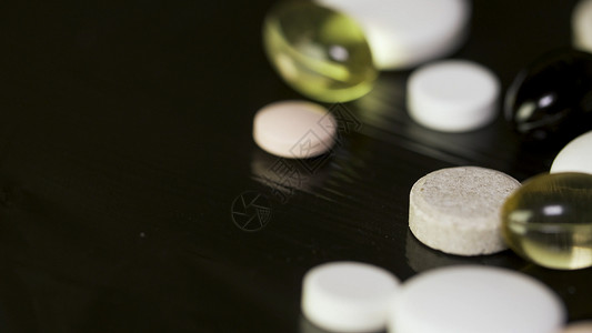 药丸旋转堆几种药物白色药片与黑色背景上的药片图片