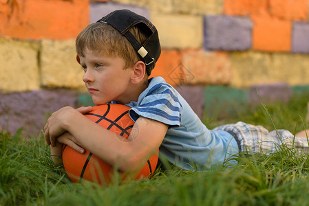 带球的家伙躺在天然的草皮上我把头放在篮球上他用双手压着球图片