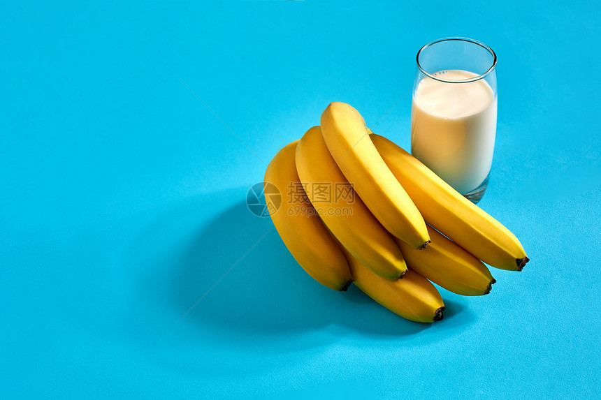 蓝色背景上的香蕉牛奶饮料和一束香蕉图片