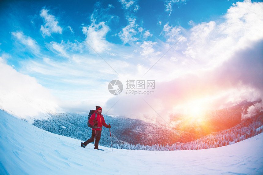 一个穿着雪鞋和登山杖的人在山上冬季旅行攀登一个登山者反对美丽的天空与云彩积极的生活方式图片