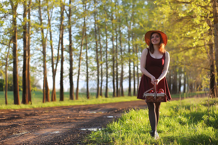 一个戴着帽子的女孩在公园散步一个提着篮子的女孩在春天散步夕阳西下图片