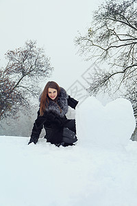女人从雪中塑造出一颗大心脏背景图片
