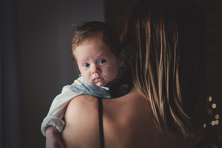 母亲肩膀上的小婴儿照片在黑色背景的窗户附近图片