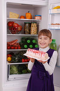 女孩在冰箱背景上拿着一根香蕉冰箱附近有健康食品的漂亮女孩冰箱里图片