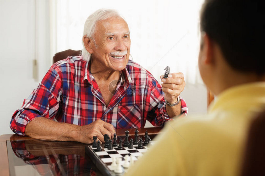 快乐的小孩在家里和老人下棋与祖父和孙子的家庭关系爷和男图片