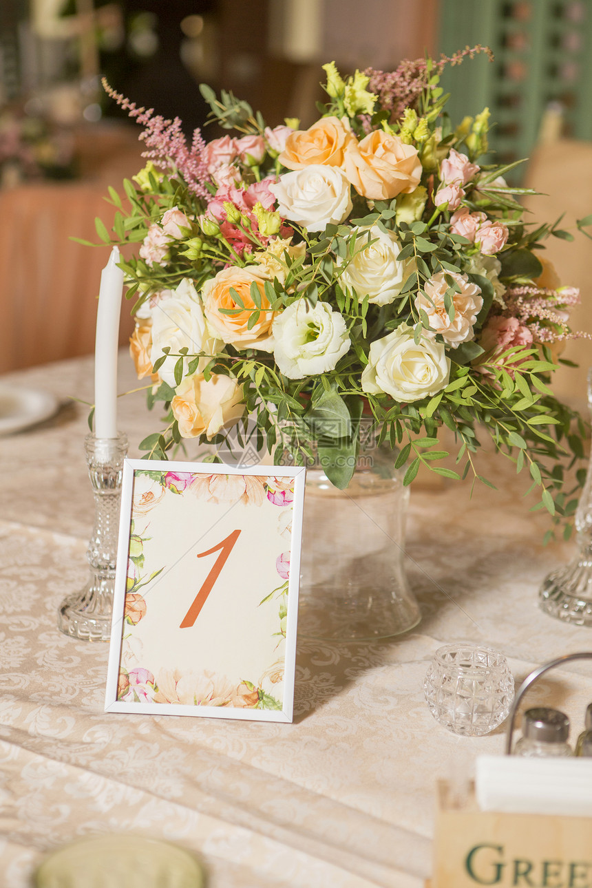 盛满玫瑰和灰色花朵蜡烛和蜜桃彩色织物的婚礼桌装饰图片