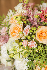 盛满玫瑰和灰色花朵蜡烛和蜜桃彩色织物的婚礼桌装饰图片
