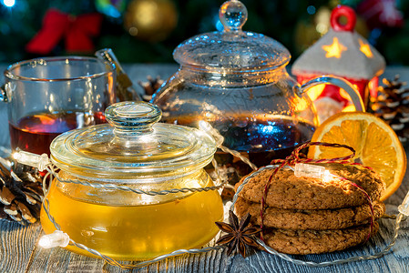 晚上在圣诞树灯前盛着一杯热茶和一罐蜂蜜图片