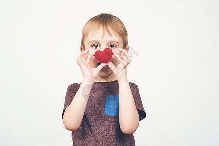 可爱的男孩玩红色编织心脏孤立图片
