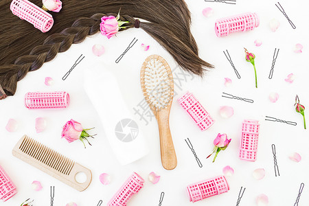 框架与梳子的头发造型卷发器卷发器和白色背景上的粉红玫瑰图片
