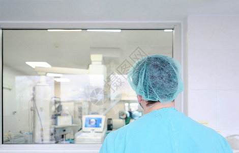 一名男子外科医生透过玻璃看医院手术室图片