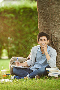 英俊的亚洲学生在公共园写论文时图片