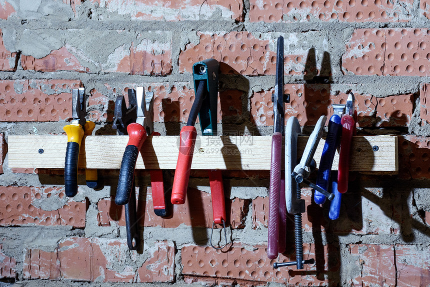 在车库车间的砖墙上设置不同的男工具Vista钳子刀具虎钳图片