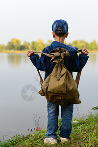 男孩背着包站在河边找水图片
