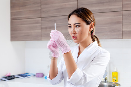 身穿白色实验室大衣和消毒手套的年轻女青年女医生美容师为注射肉毒杆菌而图片
