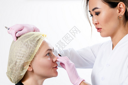 在肉毒注射帮助下对脸骨进行整顿的化妆程序女作为医生刺穿了一名年轻女子的脸盆背景图片