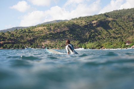 运动女运动员在冲浪板上游泳在海洋图片