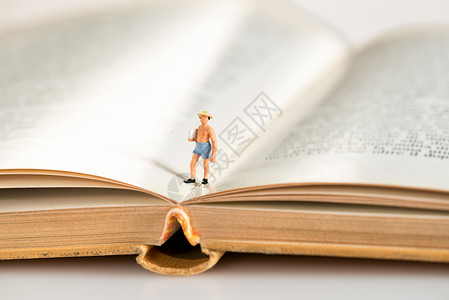 一个戴帽子的男子在一本开着的硬书上行走的微型图象图片