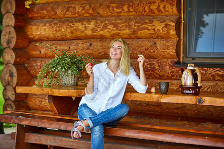 美丽的年轻女子在乡间别墅露台喝茶吃苹果图片