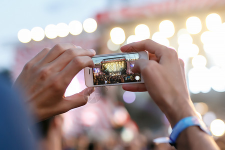 男人手里拿着智能手机和拍照在夏季户外音乐会图片
