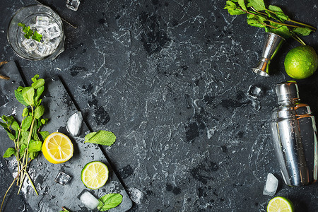 莫吉托鸡尾酒制作薄荷石灰玻璃冰配料和黑石背景上的振动筛顶视图片