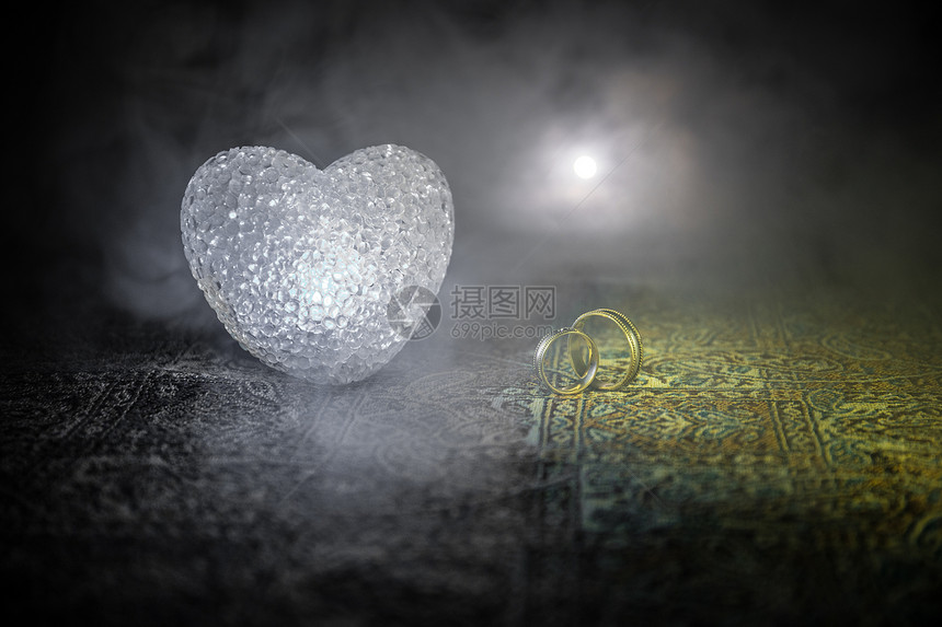 与黄金结婚戒指和心的求婚情人节的概念深色调的雾背景图片