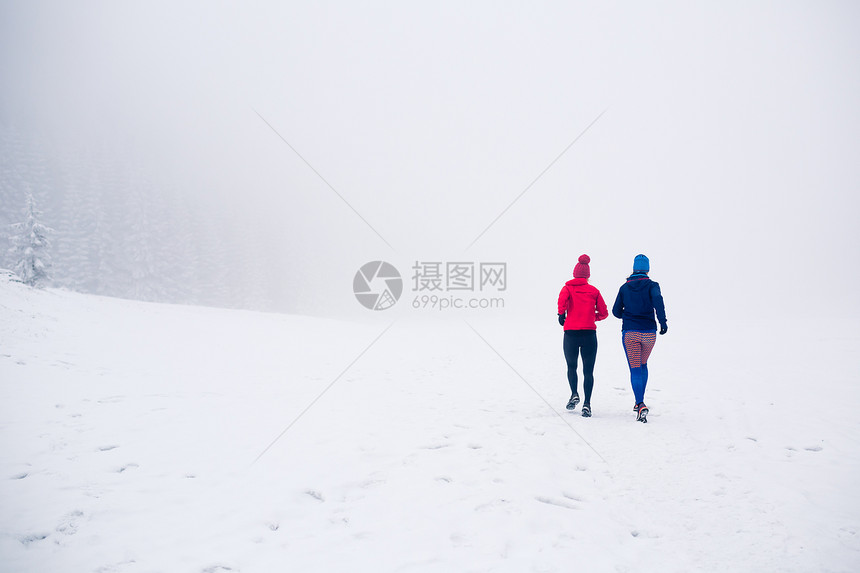 女孩们在冬天的山上一起在雪地上奔跑运动健身的灵感和动力两个女伙伴在山上跑步图片