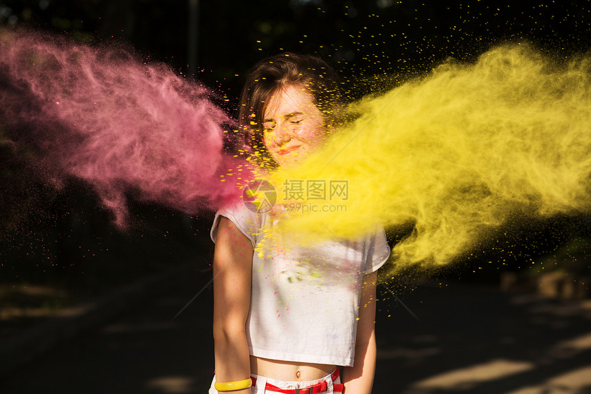 可爱的黑发女孩在霍利节上在黄粉和红色干漆图片