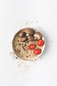 碗中生米和蘑菇以及白表面西红柿的顶端风景图片