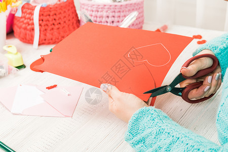 情人节主题女手把心从纸上剪下来包装好的礼物图片