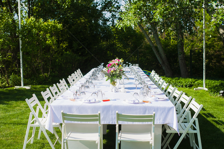 美丽的花园里有白色桌布和花卉装饰的乡村风格餐桌图片