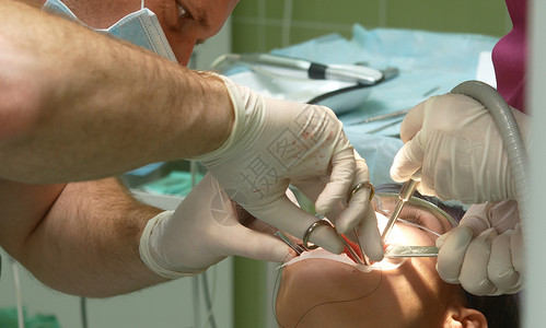 牙科医生和助理在进行治疗操纵时被病人弯下腰来图片
