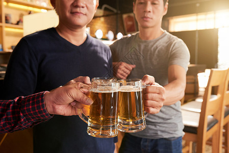 人们在酒吧里用啤酒杯敬酒图片