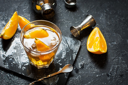 一杯加橙子和柠檬的内格罗尼鸡尾酒在黑石头桌上喝朗图片