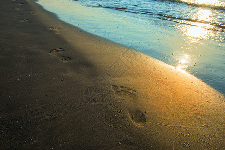 日落时的海滩波浪和脚印图片
