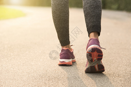 年轻跑步妇女带着日落背景在路上慢跑健康图片