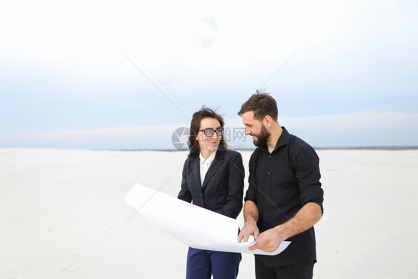设计师男子和投资公司妇女代表拿着带有计划的whatman纸图片
