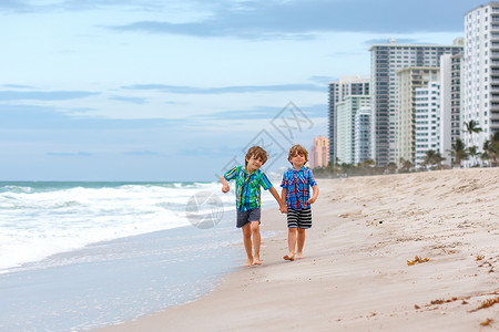 两个快乐的小孩男在海洋滩上奔跑风趣可爱的孩子兄弟姐妹和最好的朋友在美国佛罗里达州迈阿密的风雨中度背景图片