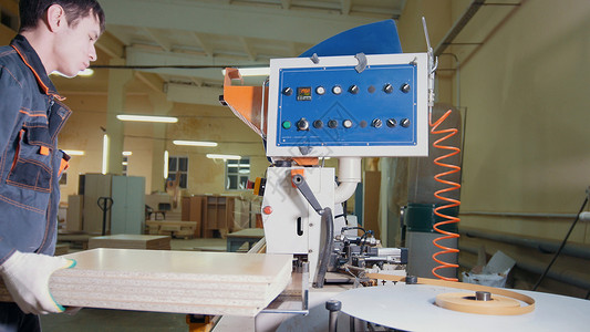 工人木匠在家具厂的缝纫机上处理板工图片