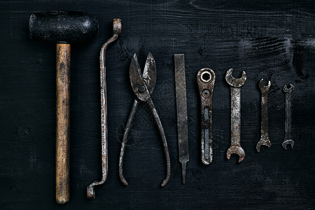 旧的生锈的工具躺在黑色的木桌上锤子凿子金属剪刀扳手顶视图复制空间图片