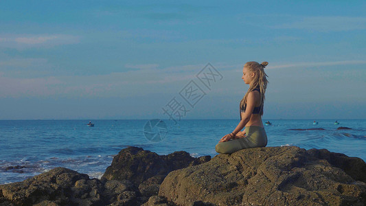 在日落时练瑜伽长女在美丽的海滩上摆着莲图片