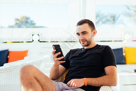 英俊的男人在沙滩上用电话放松图片