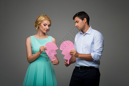 美丽的年轻夫妇抱着大粉红色破碎的心图片