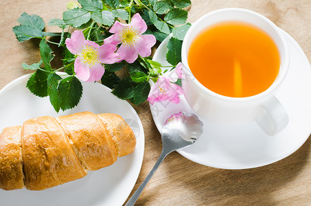 早上健康早餐一杯茶加柠檬和羊角面包在木制生锈桌边图片