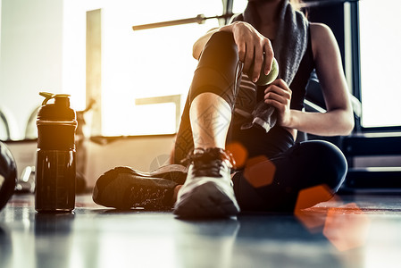 运动女在锻炼或锻炼后在健身房里坐着休息图片