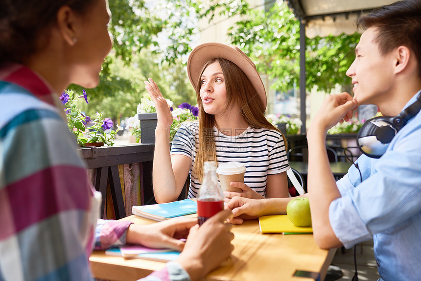 一群学生在阳光明媚的夏日外咖啡厅午餐时聊天图片