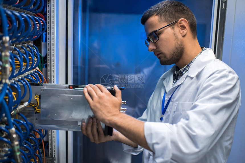 身穿实验室大衣的年轻人在与超级计算机合作时从柜子上拿出刀片服务图片