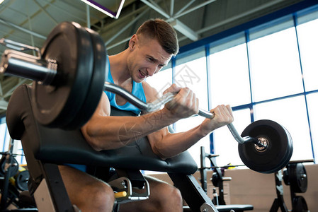 健壮的年轻男子在现代体育馆做举重运动和重型巴铃锻图片