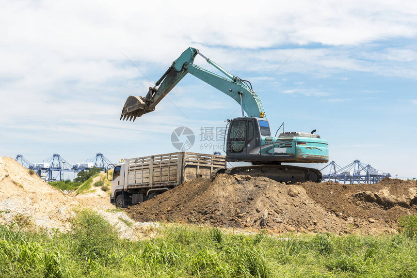 挖掘车装载并将土壤转移到山上的卡车技术机图片
