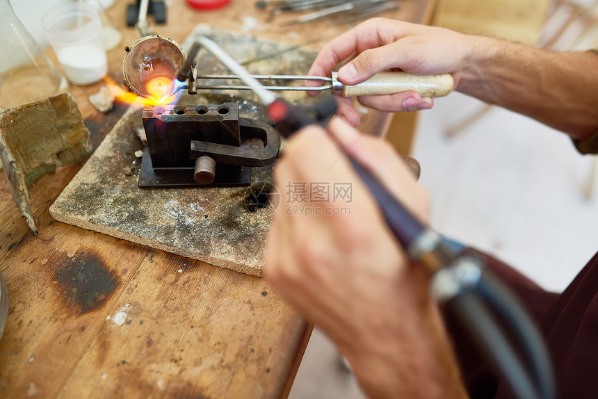 男手在工作站铸造珠宝时使用气炬在杯中熔图片